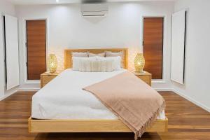 a bedroom with a large white bed with two lamps at The Lookout in Belgian Gardens