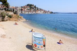 ein Strand mit Menschen auf dem Wasser und ein Schild in der Unterkunft Rooms with a parking space Sibenik - 13739 in Šibenik