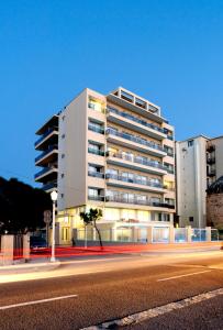 Un alto edificio bianco con una strada davanti di Hotel Riviera a Città di Rodi