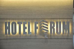un cartello metallico che legge l'hotel che corre su una parete di legno di Hotel Forum a Baranzate