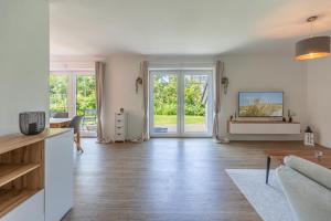Una sala de estar con suelos de madera y paredes blancas. en Ferienhaus Norderreihe, en Ostenfeld