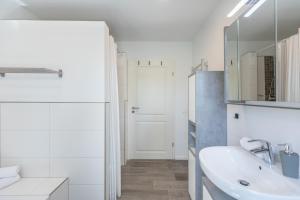 Un baño blanco con lavabo y espejo. en Ferienhaus Norderreihe, en Ostenfeld 28 fotos más