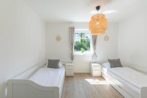Una habitación blanca con dos camas y una ventana. en Ferienhaus Norderreihe, en Ostenfeld