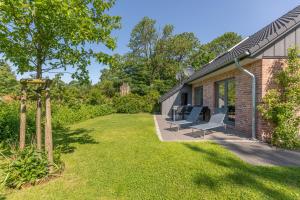 una casa con un patio con sillas y árboles en Ferienhaus Norderreihe, en Ostenfeld