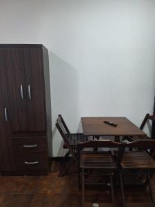 Una mesa y sillas de madera junto a un armario. en Suites dos Anjos, en Arraial do Cabo