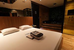 a bed with a suitcase sitting on top of it at Motel Riviera in Araraquara