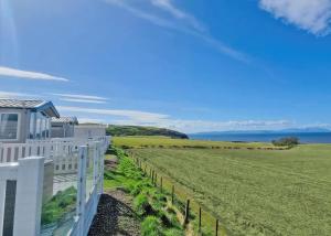 una casa blanca con una valla y un campo en Heads Of Ayr Holiday Park, en Ayr