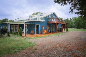 una casa blu con portico e terrazza di The Blue Barn at the MeadowCreek a Murfreesboro