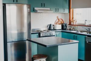 a kitchen with blue cabinets and a stainless steel refrigerator at Dalton St House in Parkes