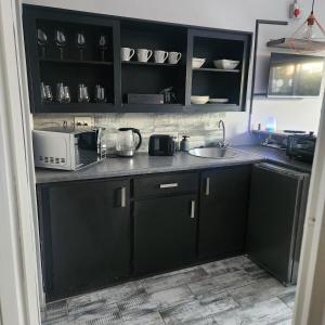 a kitchen with black cabinets and a microwave at Modern Comfort at 44 Biddulph in Harrismith
