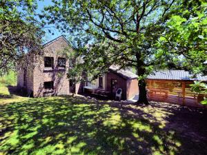 a house with a tree in front of a yard at Cozy Cottage in Durbuy with Garden in Barvaux