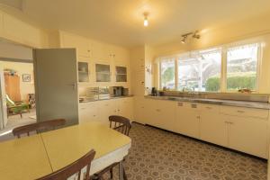 Una cocina grande con gabinetes blancos y una mesa. en Classic Kiwi Bach Southbay, en Kaikoura 6 fotos más