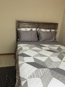 ein Schlafzimmer mit einem Bett mit einer Bettdecke und Kissen in der Unterkunft Constant Spring Oasis in Kingston