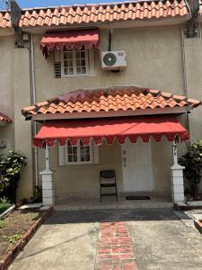 ein Haus mit einer roten Markise und einem Stuhl darunter in der Unterkunft Constant Spring Oasis in Kingston