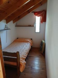 a small bedroom with a bed and a window at Cabañas El Duende in Quines +1 photo