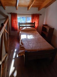 a bedroom with a bed and a window with red curtains at Cabañas El Duende in Quines