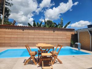 a table and chairs next to a swimming pool at Chalés Mirante da Lua Chalé 3 in Cavalcante
