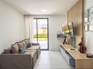 a living room with a couch and a television at Casa Turquesa Pé na areia Piscina infinita Pet friendly Condomínio fechado in Itacimirim