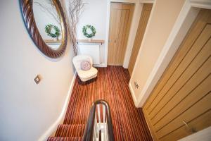 a hallway with a staircase with a mirror and a chair at Chester Apartments in Chester