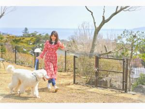a woman walking a white dog near a fence at LiVEMAX Resort Izu Kogen Terrace & Spa in Ito
