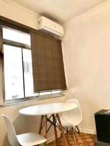 ein weißer Tisch und Stühle in einem Raum mit einem Fenster in der Unterkunft Ap Demetrio Ribeiro in Água Boa