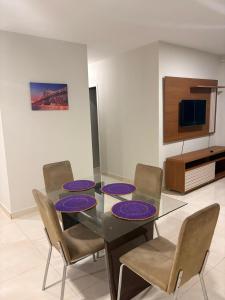 a dining room with a glass table with purple plates on it at Apto de 3 Quartos Vista lateral do Mar a 2km da praia do Araçagy in São Luís