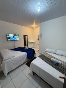 a hotel room with two beds and a flat screen tv at Pousada Center in Barreirinhas
