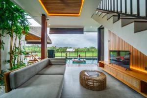 a living room with a couch and a tv at Kairos Villa Ubud by Omkara Experience in Ubud