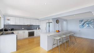 a kitchen with white cabinets and a counter with stools at Aquavista Beach, Lake, Sun, and Sand in Budgewoi