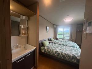 a small bedroom with a bed and a sink at サザンヒルズガーデン in Fujikawaguchiko