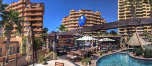 a swimming pool with tables and umbrellas and buildings at Bella Sirena BA 505 As Good As It Gets Beautiful Ocean View Condo in Puerto Peñasco