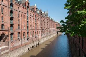 a canal in front of a large brick building at Appartements in der historischen Deichstrasse contactless Check in in Hamburg