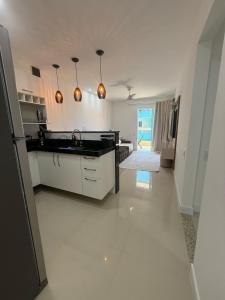a kitchen with white cabinets and a black counter top at Arraial do Cabo RJ - Golden Lake in Arraial do Cabo