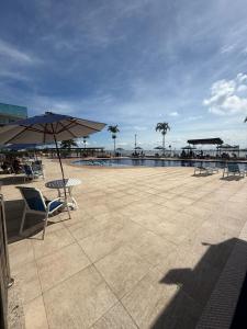 a patio with chairs and an umbrella and a pool at Arraial do Cabo RJ - Golden Lake in Arraial do Cabo