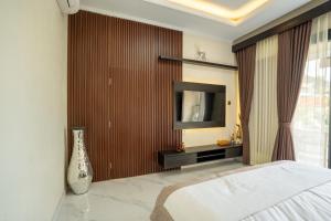 una camera da letto con un letto e una TV a parete di Pondok Manik Uma a Tabanan