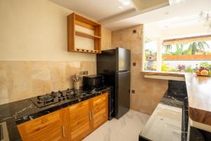 una cucina con frigorifero nero e armadietti in legno di Pondok Manik Uma a Tabanan
