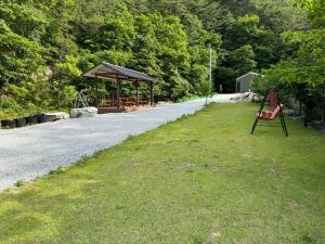 a bench sitting on the grass next to a road at Yangyang Dalpaengi Pension in Yangyang