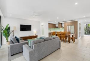 a living room with a couch and a dining room at Vista Verde - A Temple Resort Family Treasure in Palm Cove
