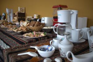 a table with plates of food and a coffee maker at Hostal Oasis del Refugio in Salta