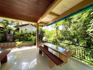 a patio with a wooden table and benches on a balcony at Guesthouse Gusti Putu Oka in Ubud