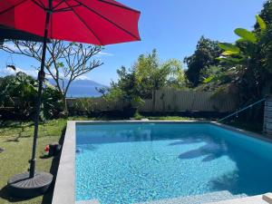 a red umbrella sitting next to a swimming pool at Studio Kumbaya in Faaa