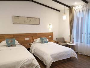 a hotel room with two beds and a window at Zhangjiajie Tingyutang Little Yard in Zhangjiajie