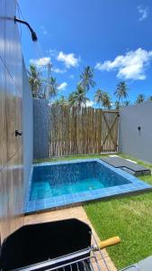 ein Schwimmbad in einem Garten neben einem Zaun in der Unterkunft LOFT Rio 102 - Refúgio Romântico Inclusivo com Piscina Privativa - bem prox a Vilas Gastronômicas, Polo de Artesanato e Associação Peixe-boi in Pôrto de Pedras