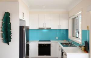 a kitchen with white cabinets and a blue accent wall at Horizons in Wamberal
