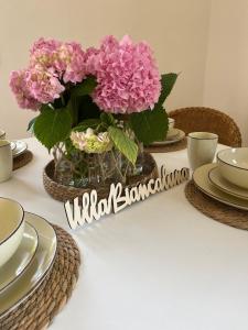 une table avec un vase de fleurs roses sur elle dans l'établissement Villa Biancaluna, à San Felice del Benaco