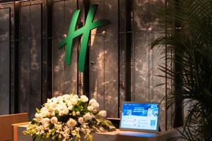 a table with a vase of flowers and a laptop at Holiday Inn Guangzhou Zhujiang New Town in Guangzhou
