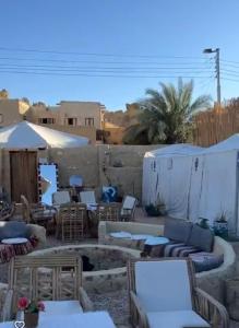 a patio with tables and chairs and a fire pit at Muhra Camp in Siwa +8 photos