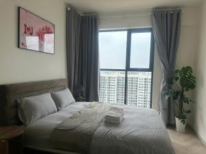 une chambre avec un grand lit et une grande fenêtre dans l'établissement Căn hộ cao cấp Masteri Centre Point Vinhomes Grand Park Quận 9 TPHCM, à Gò Công