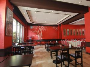 een eetkamer met rode muren en tafels en stoelen bij Hotel Supreme in Baguio
