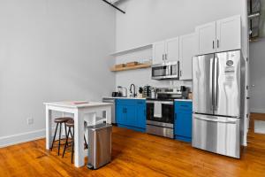 a kitchen with blue cabinets and a stainless steel refrigerator at Charming 3bed Mill | Gym | Trail in Greenville +8 photos